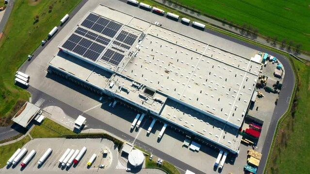 Industry with low carbon footprint. Industrial warehouses with solar panels on the roof. Technology park and factories from above.

