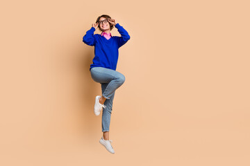 Fototapeta na wymiar Full length portrait of gorgeous overjoyed person jump arms touch eyeglasses empty space isolated on beige color background