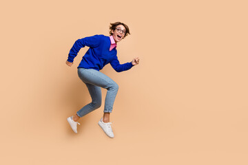 Full size profile portrait of impressed cheerful girl jump rush empty space isolated on beige color background