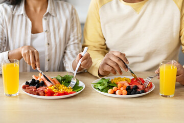 Obraz na płótnie Canvas Unrecognizable couple sitting together at kitchen, have breakfast