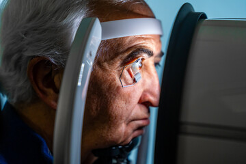 Senior man looking through a laser machine to treat glaucoma