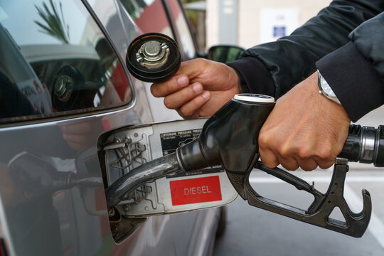 Hands of a man filling up a car with gasoline at a gas station