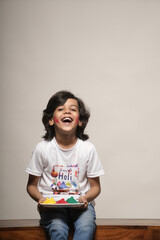 Young kid boy celebrating holi standing isolated on plain background