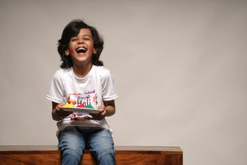 Young kid boy celebrating holi standing isolated on plain background