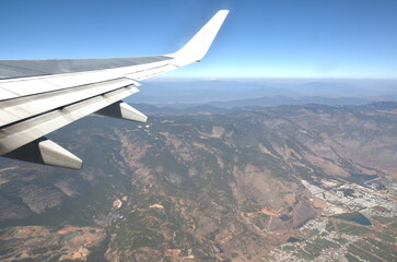 plane wing and mountain background on sky through window frame