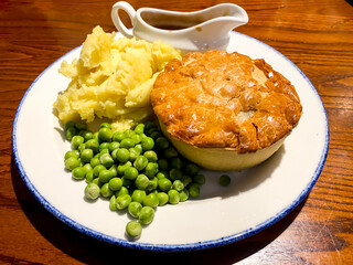 Chicken pie with mashed potato, peas and gravy for lunch at a pub.