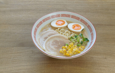 a bowl of tonkotsu miso ramen topped with boiled egg, pork slices and spring onion 