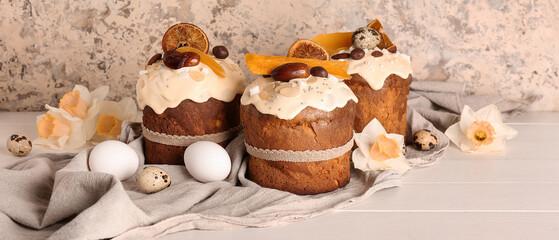 Obraz na płótnie Canvas Easter cake with narcissus and eggs on white wooden table near beige grunge wall