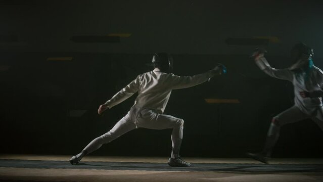 Side full footage of two fencers starting sword fight in dark hall, they attacking and parrying