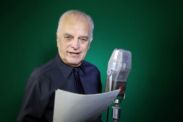 Mature journalist reporting the news on the radio. Announcer speaking into microphone and reading...