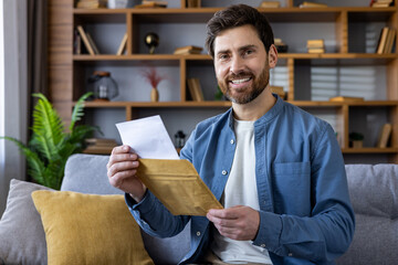 Man opening an envelope while sitting on couch