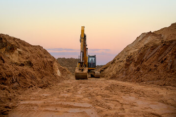 Excavator digs a large trench for pipe laying. Backhoe during earthmoving at construction site....