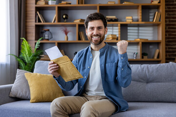 Excited man celebrating success with letter at home