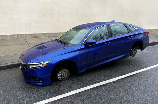 Car without wheels on street. Thieves stealing tires and rims from car. Tire, rim thefts a widespread problem across USA. Wheel Theft from car. No wheels, incident. Theft Car parts. Wreck on parked.