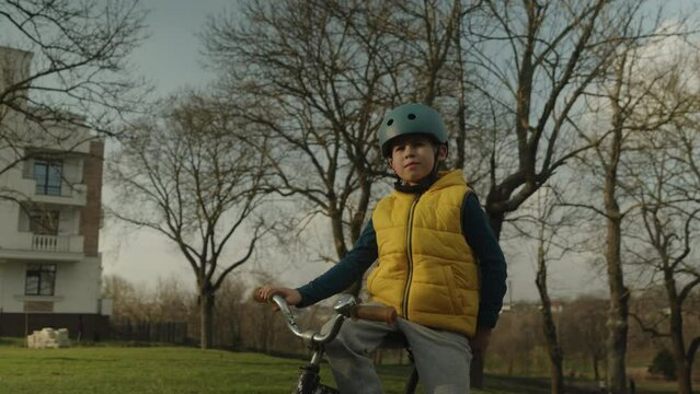 Caucasian child in safety helmet riding bik outside in autumn park. Child in safety helmet riding bike. Kid on bicycle. Happy child in helmet
