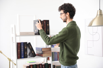 Male student taking book from shelf in library