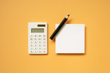 Office supply. Calculator, notepad, pencil on orange desk background. flat lay, top view, copy space