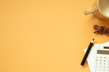 Workspace concept. Notepad, pencil, calculator, mug cup, plant on orange desk background. flat lay,...