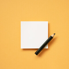 White blank memo notepad and pencil on orange desk background. top view, copy space