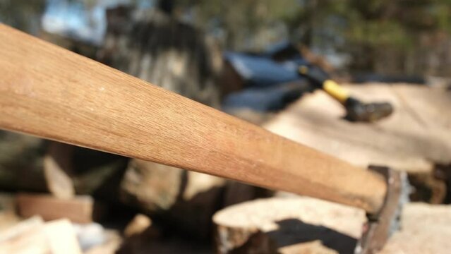 Close up of home made Russian style ax impaled in oak stump or slab of wood ready to be split and processed into firewood.