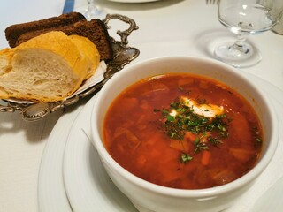 A plate of orange borscht with bread on the table