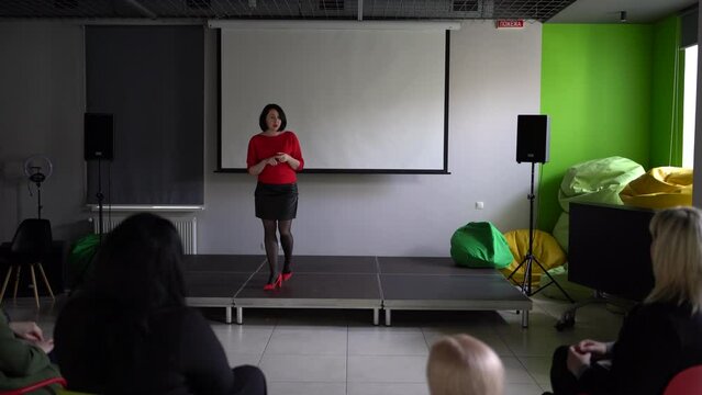 a woman gives a speech on stage in front of her colleagues