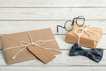 Gift box, envelope, bow tie and glasses on a wooden background. Happy Birthday, Father's Day...
