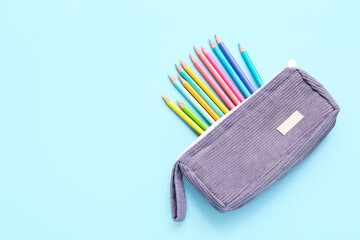 Case with many colorful pencils on blue background