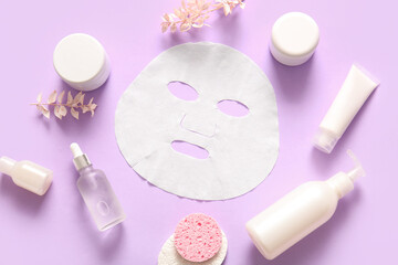 Fototapeta na wymiar Facial sheet mask with different cosmetic products on lilac background