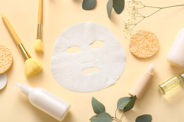 Facial sheet mask with different cosmetic products, leaves and gypsophila flowers on yellow...
