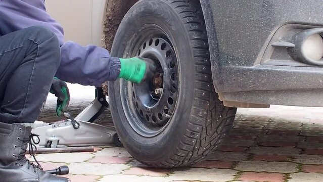 Kandra, Bashkortostan, Russia - December 01, 2023: Car mechanic removing car wheel covers using drill tool in service garage.