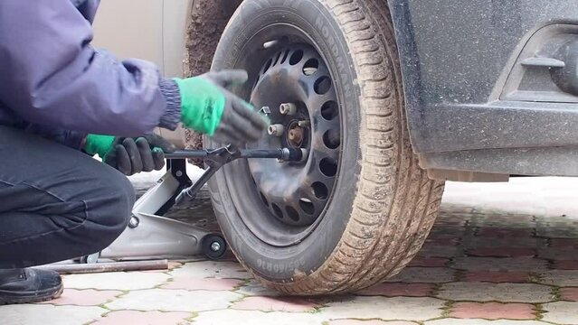 Kandra, Bashkortostan, Russia - December 01, 2023: Car mechanic removing car wheel covers using drill tool in service garage.