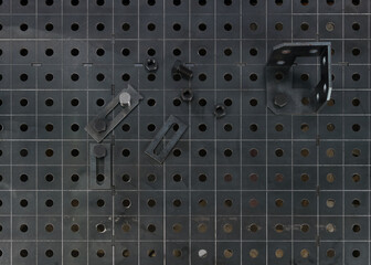 black metal background with cage and holes, a set of different clamps for fixing welding parts, bolts, corners