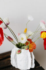 Stylish summer bouquet on rustic wooden bench. Beautiful red and yellow poppies in modern vase. Summer wildflowers, floral still life. Happy Mothers day, space for text