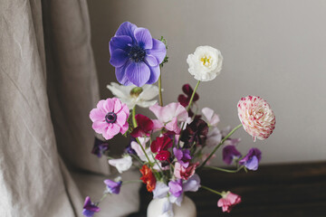 Summer flowers in vase, rustic still life. Beautiful colorful anemone, ranunculus, lathyrus on aged wooden bench with linen curtains. Floral moody wallpaper. Space for text