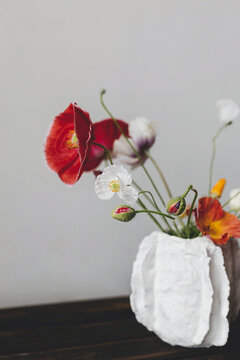 Stylish summer bouquet on rustic wooden bench. Beautiful red and yellow poppies in modern vase. Summer wildflowers, floral still life. Happy Mothers day, space for text