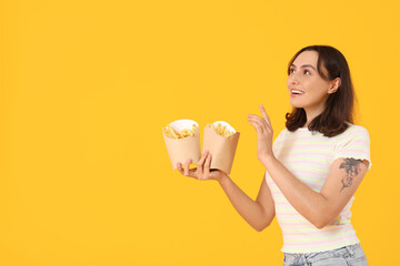 Young woman with french fries on yellow background