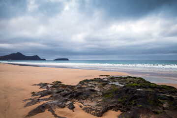 Fototapeta na wymiar Dramatic coastal landscape with wet dark rocks. Beach of Porto Santo