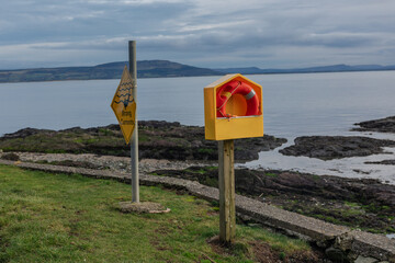 A lifebuoy on a shore stand and strong currents in the water sign