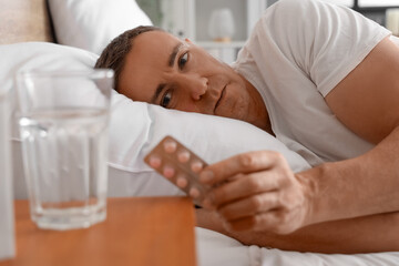 Middle-aged man in bed taking pills before sleep