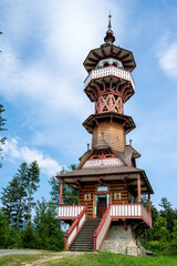Wooden lookout tower in old wooden wallachiavillage with green meadow in summer. Roznov pod Radhostem. Czech Republic.