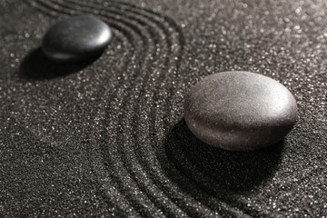 Fototapeta na wymiar Stones on dark sand with lines in Japanese rock garden. Zen concept