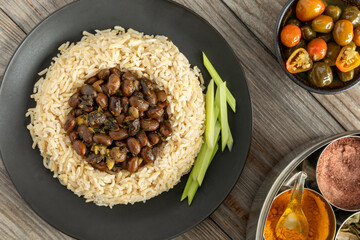 Black soybeans cooked in spices served with brown basmati rice and celery stalks. Bhat ki Chudkani - a traditional dish of the Kumaon region. Pickled chilies and a box with spices on the side. 