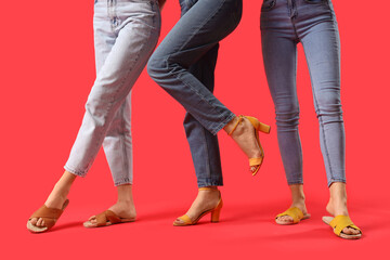 Female legs wearing different sandals on red background