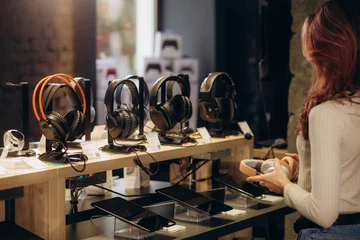 Wanddecoratie Muziekwinkel Girl buying headphones in audio store, music fan  © Roman