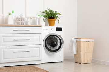 Interior of light room with washing machine and laundry basket