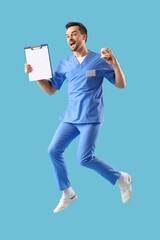 Portrait of male dentist with jaw model and clipboard jumping on blue background