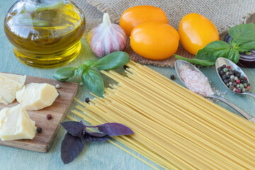 recipe for pasta with tomatoes or macaroni al pomodoro close-up of spaghetti, yellow tomatoes, olive oil, basil, parmesan cheese, onion, garlic and spices.
