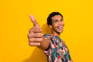 Photo of excited funky man wear print t-shirt showing you thumb up isolated yellow color background