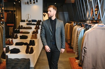sale, shopping, fashion, style and people concept - elegant young man in suit in mall or clothing store